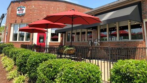A brick building with a red awning and outdoor seating area with red umbrellas. - Charming 1910 Luxury Condo in Downtown Fuquay - Steps to Parks & Eateries (Fuquay-Varina)