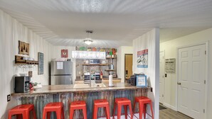 A kitchen with a bar area, red stools, and various kitchen appliances. - Walkable Lead Condo: 5 Mi to Terry Peak Ski Area! (Lead)