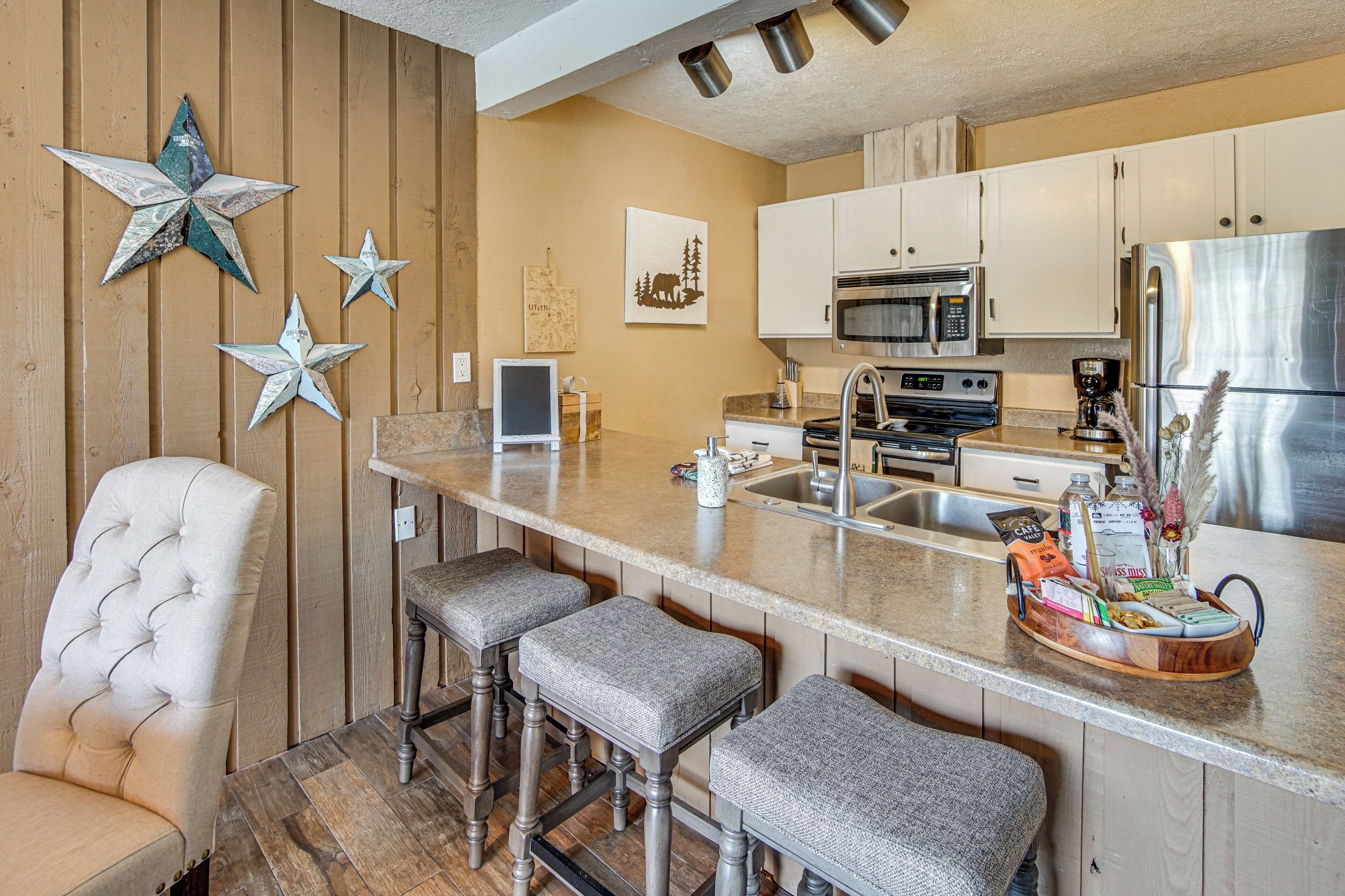 A kitchen with a bar area, wooden paneling, and a large refrigerator.