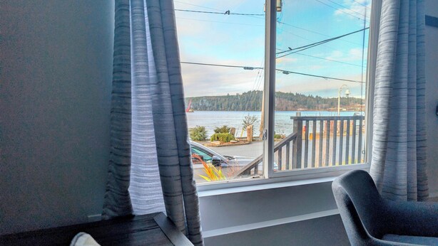 A room with a view of a lake, a chair, and a bed.
