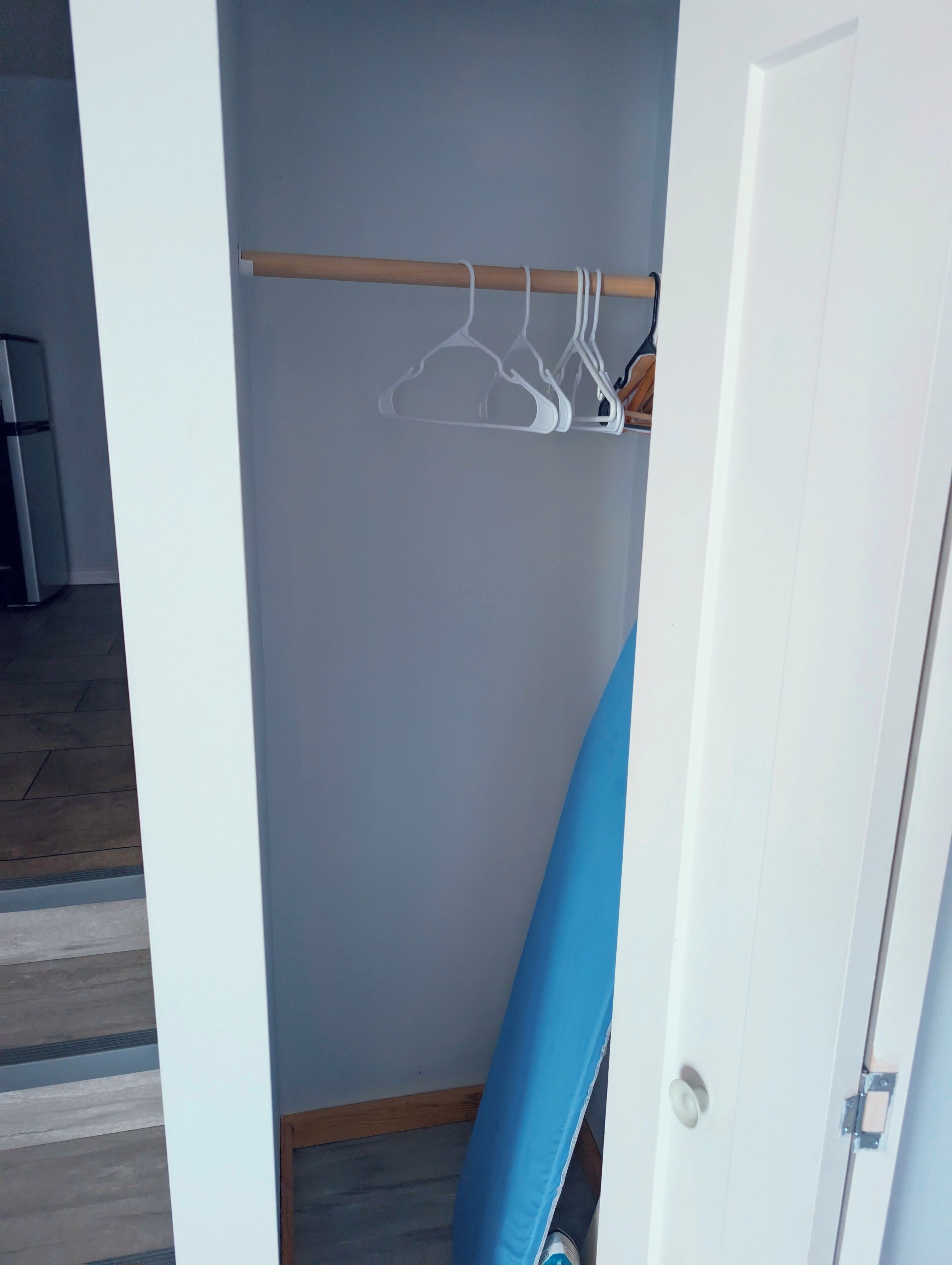 Une pièce avec un plancher en bois, une porte blanche et une chaise bleue.