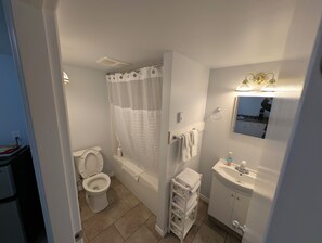A bathroom with a toilet, bathtub, shower curtain, towel rack, and sink.