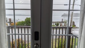 A view through a door with a view of a waterfront, including a dock and vegetation.