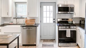 A modern kitchen with white cabinets, a stainless steel dishwasher, a microwave, and an oven.