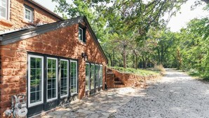 A stone building with large windows and a gravel driveway.