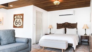 A bedroom with a bed, bedside tables, a nightstand, a sofa, and a wooden ceiling.