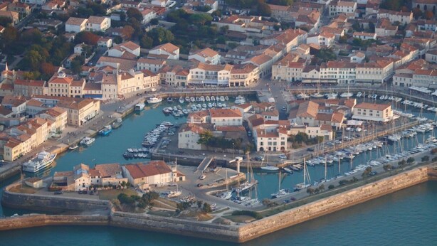 An aerial view of a coastal town with a marina, historic buildings, and a fortified wall. - Individual house .  (Le Bois plage)