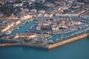 An aerial view of a coastal town with a marina, historic buildings, and a fortified wall.