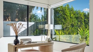 Een moderne kamer met een groot raam, een tafel met een vaas, een lamp en twee stoelen.