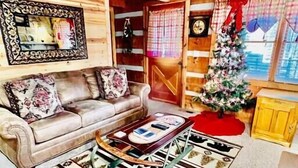 L'intérieur chaleureux d'un chalet en bois, avec un canapé, une table basse et un sapin de Noël.