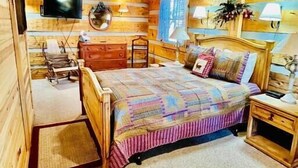 Une chambre confortable dans un chalet en rondins, avec un lit, une commode et un téléviseur.