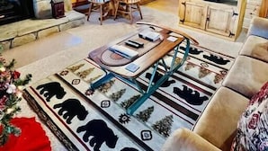 L’intérieur chaleureux d’un chalet en bois avec une cheminée en pierre, un coin repas, une cuisine et un salon équipé d’une télévision.