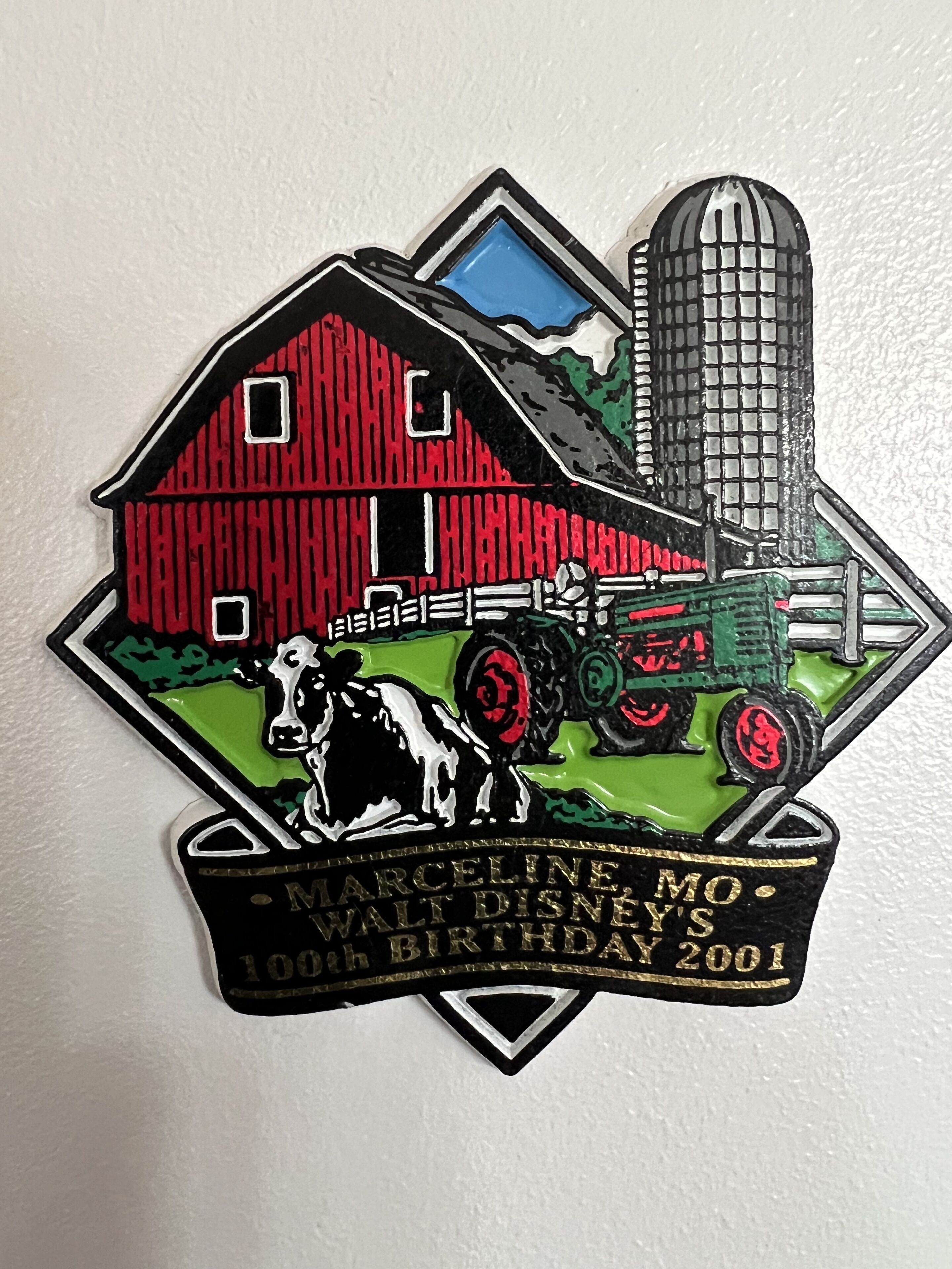 A farm-themed pin with a barn, tractor, and cow, and text indicating "Marceline Mo. Walt Disney's 100th Birthday 2001".