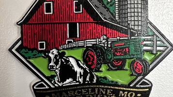A farm-themed pin with a barn, tractor, and cow, and text indicating "Marceline Mo. Walt Disney's 100th Birthday 2001".
