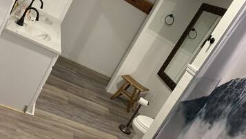 A bathroom with a white sink, wooden floor, and a toilet.
