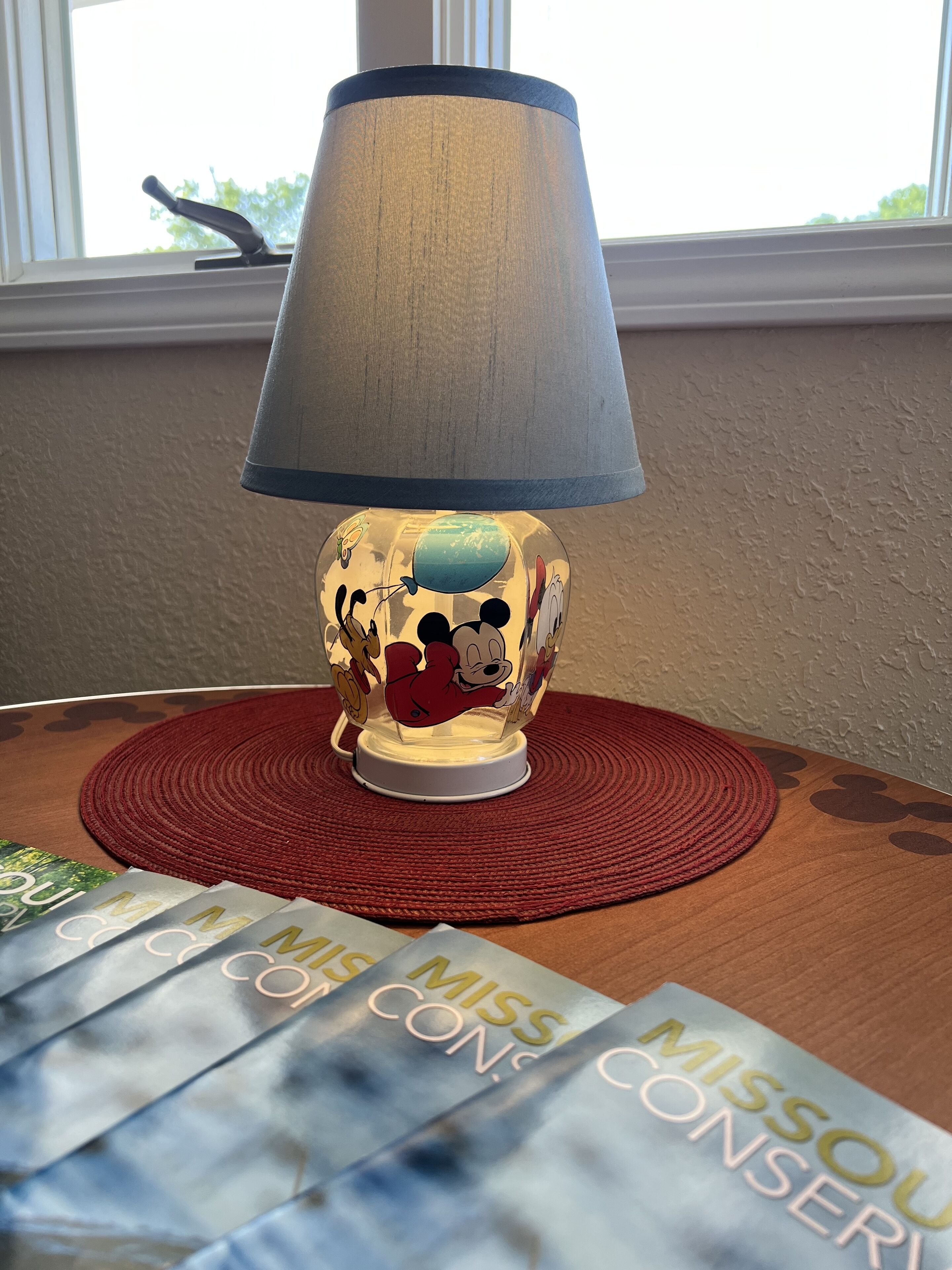 Een lamp met een Mickey Mouse ontwerp op een houten tafel met een rode onderzetter.