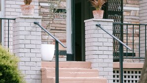 A building with a stone facade, a set of stairs leading to a door, and two potted plants on the steps. - Vintage Charm by Number Sixteen Beach | 🐶 friendly (Rye)