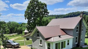 A two-story house with a sloped roof, a garage, and a well-maintained lawn. - Remodeled country farmhouse, 3 min drive from Mississippi River, Peaceful/Clean. (Genoa)