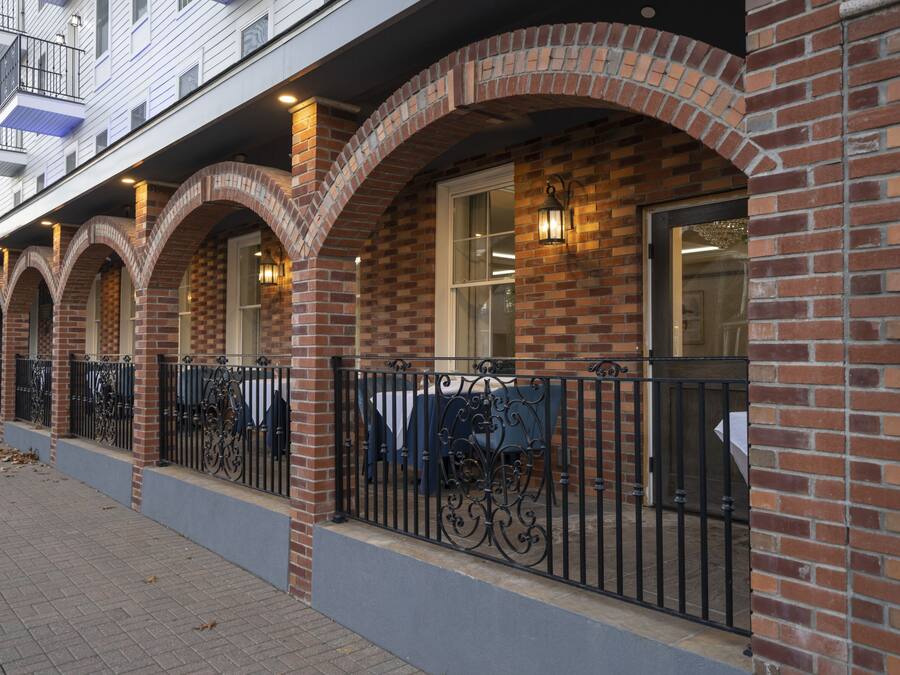 A row of brick buildings with arched windows and a covered outdoor seating area.