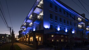 Un hotel de varios pisos con balcones, mobiliario exterior y una fachada bien iluminada.