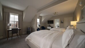 Una habitación de hotel con una cama grande, un escritorio, una silla y un televisor.