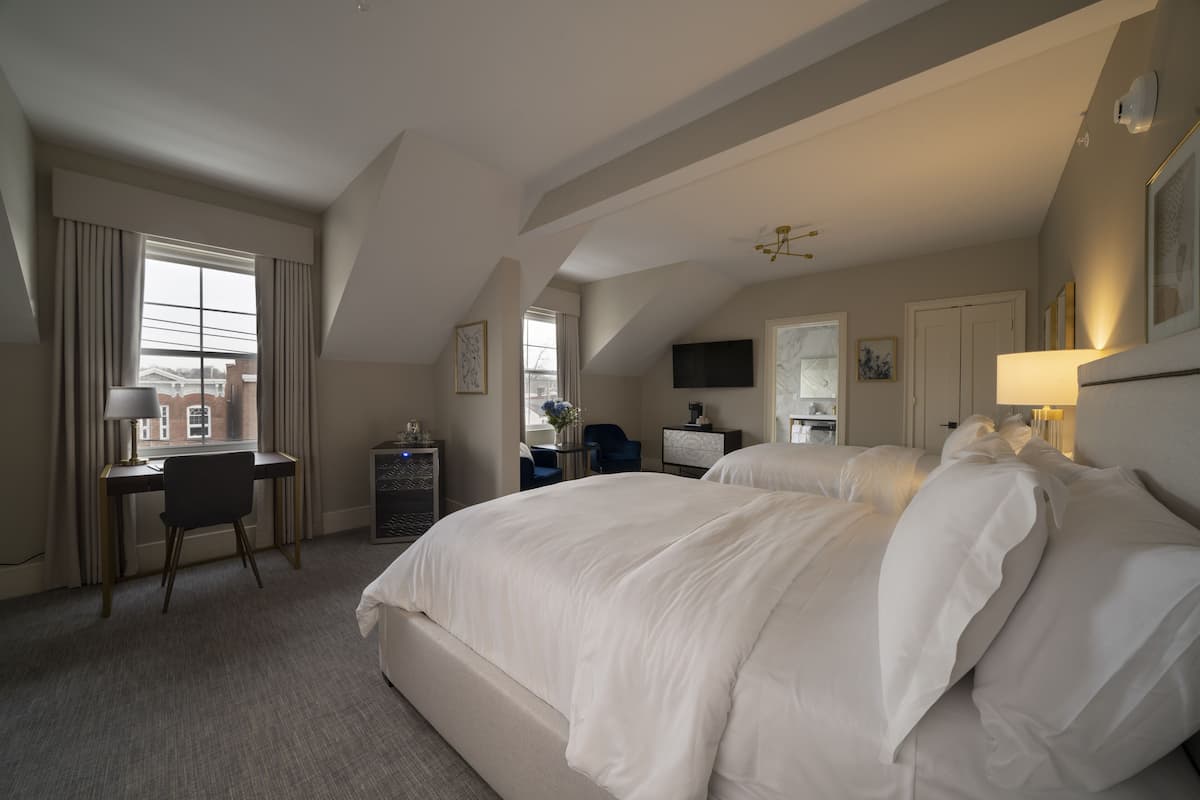 A hotel room with a large bed, a desk, a chair, and a TV.