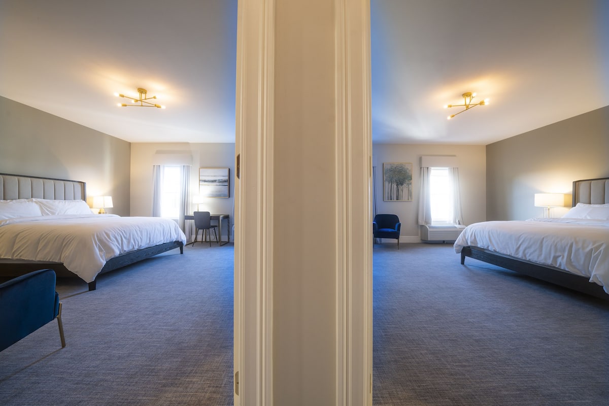 A hotel room with two beds, a desk, and a chair.