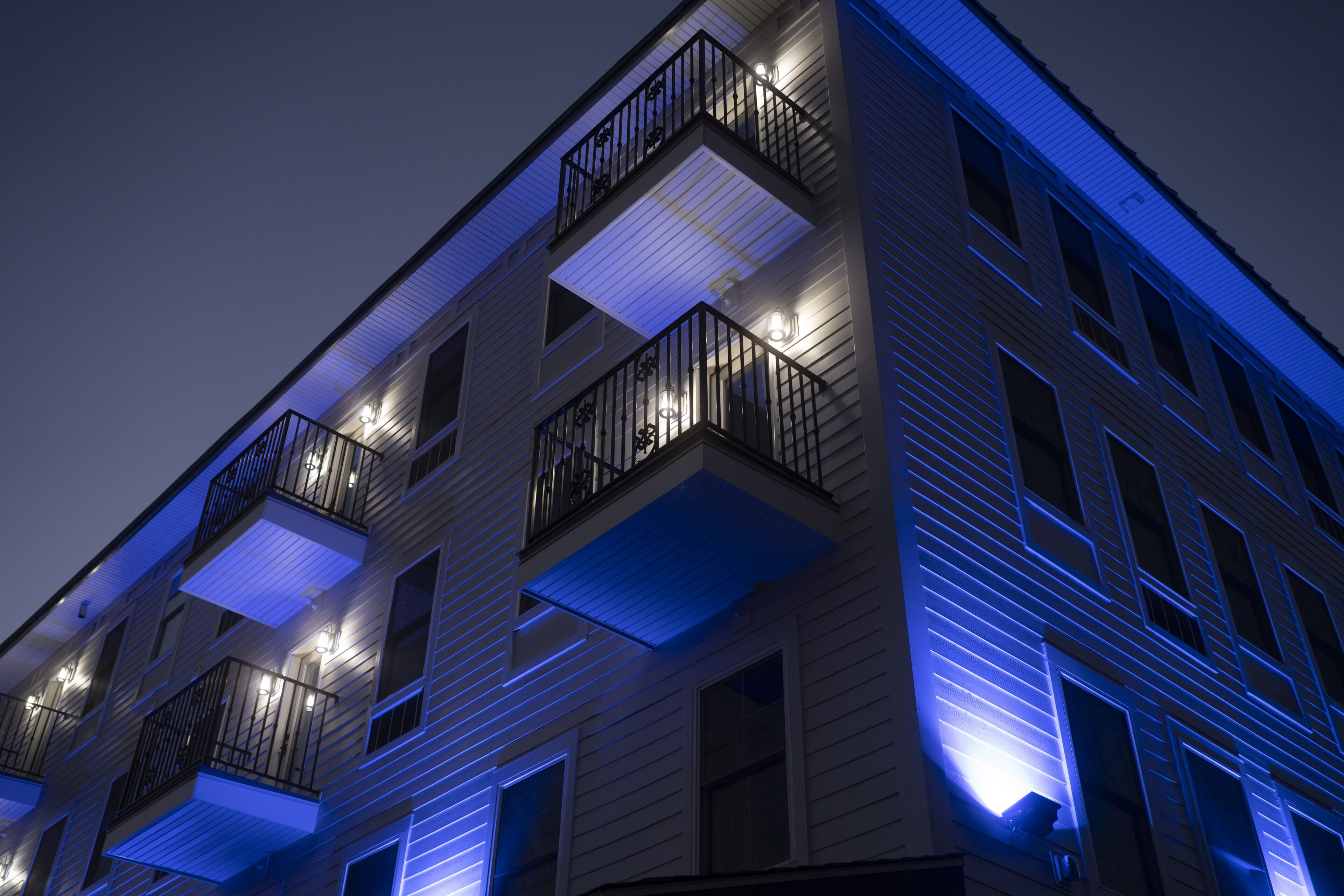 Un edificio de varios pisos con balcones e iluminación exterior.