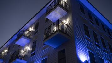 Un edificio de varios pisos con balcones e iluminación exterior.