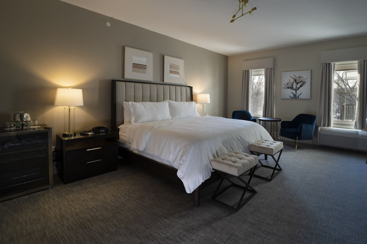 A hotel room with a large bed, bedside tables, a desk, and a chair.