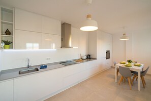 A modern kitchen with a built-in oven, a sink, and a dining area with a table and chairs. - Apartamento Liria (La Mata) (Torrevieja)