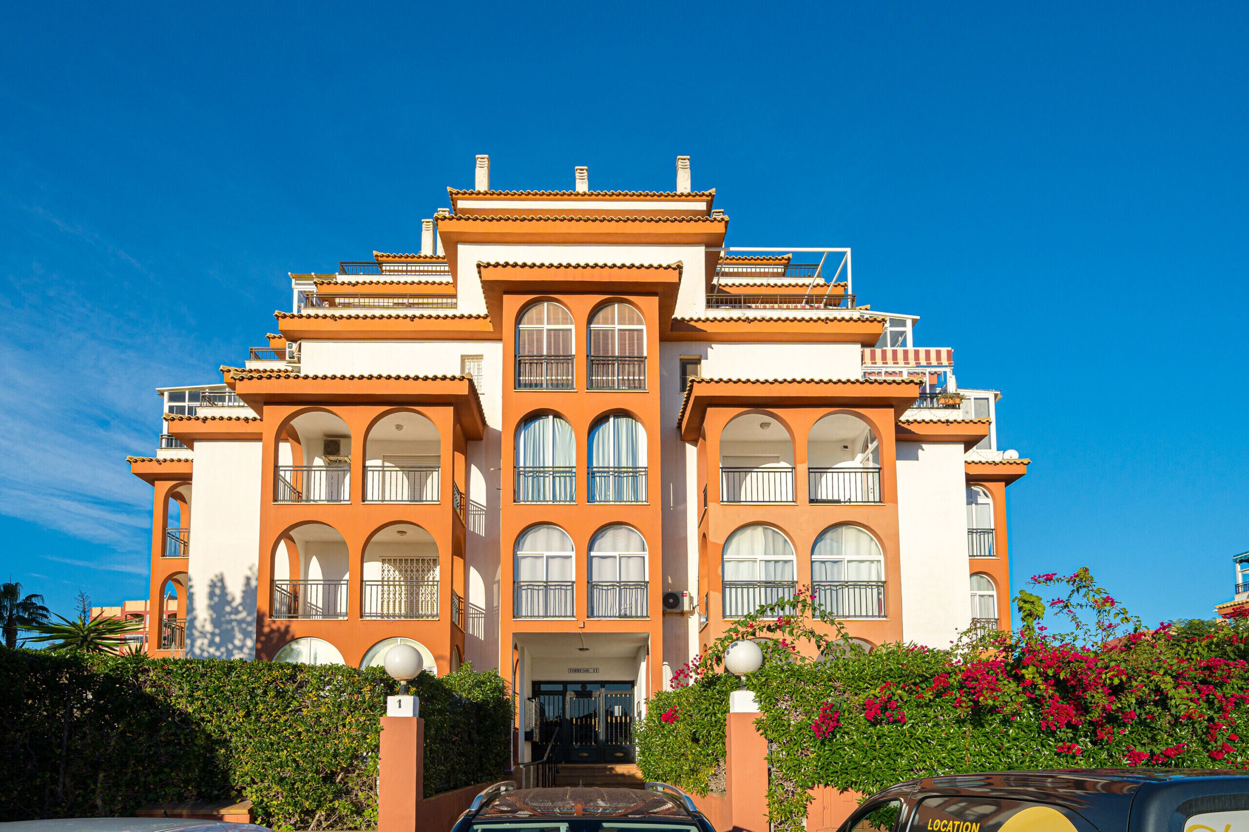 A large, multi-story building with a symmetrical facade, arched windows, and balconies.