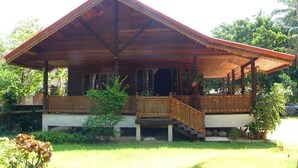 A wooden house with a porch and staircase, surrounded by greenery. - Handcrafted Lodge short walk from Mae Nam beach (Koh Samui)