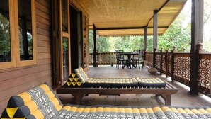 A covered outdoor seating area with wooden benches and cushions, a table, and chairs. - Handcrafted Lodge short walk from Mae Nam beach (Koh Samui)