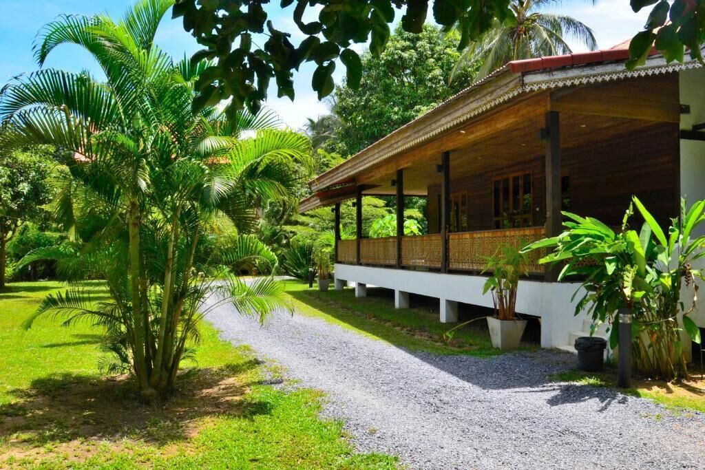 A covered outdoor area with a gravel path leading to a building with a wooden roof and white walls.