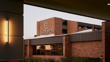 A Sheraton hotel with a prominent 'Sheraton' sign on the facade, large windows, and a brick exterior.