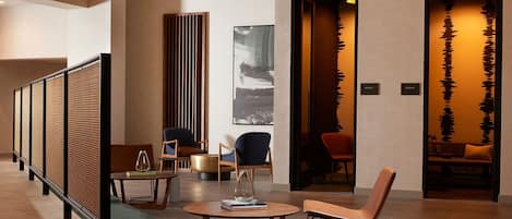 A modern hotel lobby with a reception desk, seating area, and a decorative wall with abstract art.