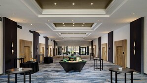 A hotel lobby with a long corridor, multiple doors, and a central decorative table. - Sheraton Grand Rapids Airport Hotel (Grand Rapids)