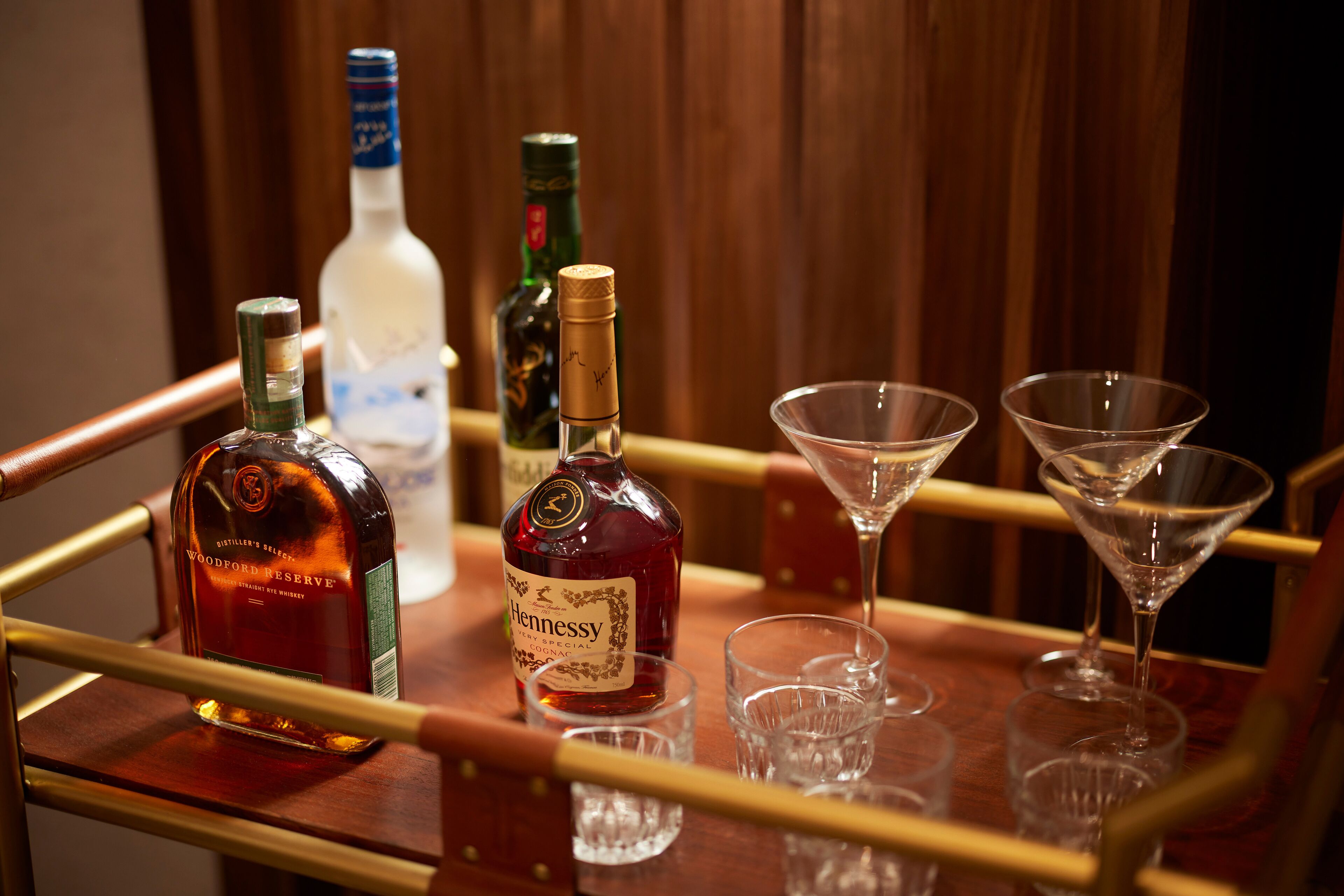 A bar area with bottles of liquor and empty martini glasses on a wooden bar counter.