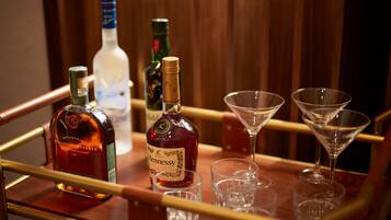 A bar area with bottles of liquor and empty martini glasses on a wooden bar counter.