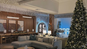 A modern hotel lobby with a large Christmas tree, seating areas, and a reception desk. - Sheraton Grand Rapids Airport Hotel (Grand Rapids)