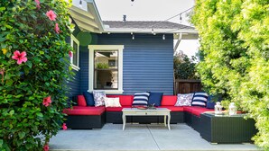 A blue house with a red and black outdoor seating area, a white table, and steps leading up to the entrance. - House in Prime Belmont Heights Near Beach w/ Gym and Garage (Long Beach)