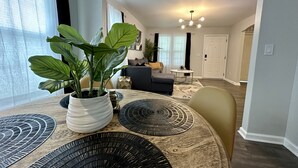 A modern living room with a round dining table, a potted plant, and a black and white patterned rug. - Beautiful Modern House 5 minutes To Downtown Raleigh (Raleigh)