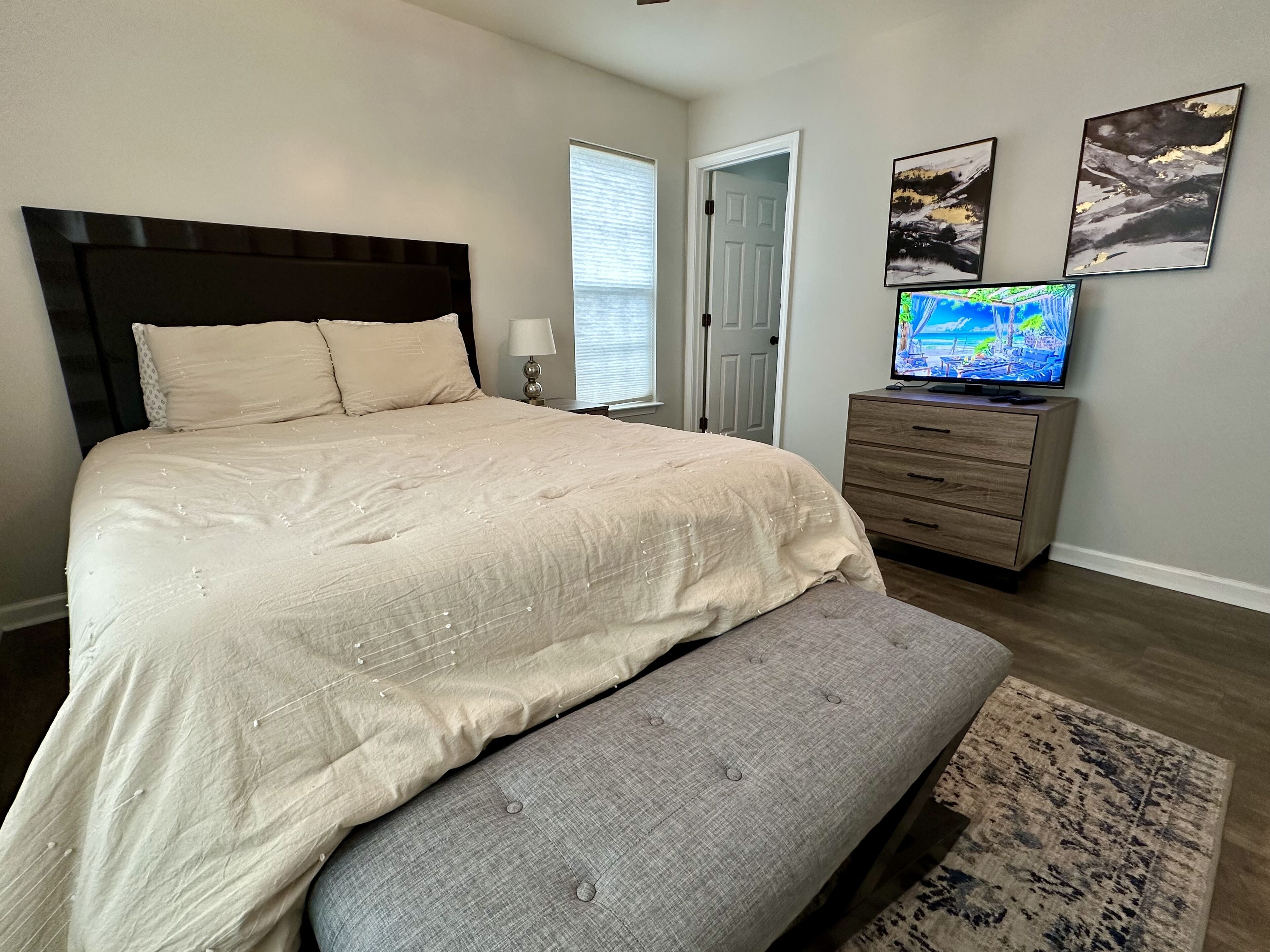 Ein Schlafzimmer mit einem großen Bett, einer Bank, einem Schminktisch und einem Fernseher.