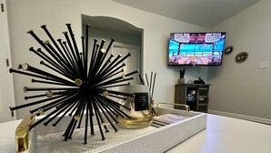 A modern kitchen with a decorative black and gold centerpiece, a television on the wall, and a small cabinet. - Beautiful Modern House 5 minutes To Downtown Raleigh (Raleigh)