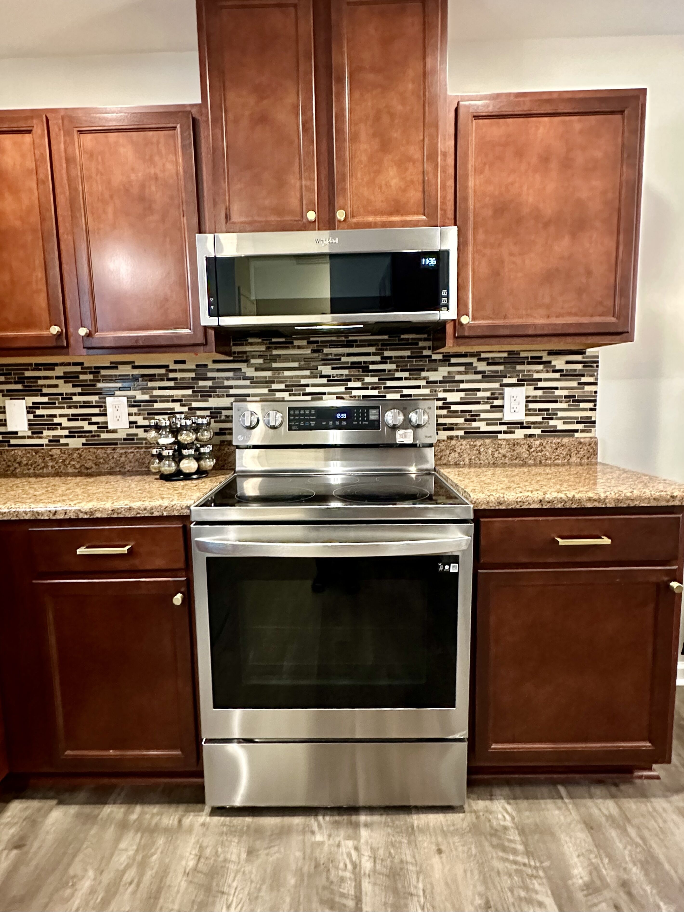 A kitchen with wooden cabinets, a stainless steel microwave, an oven, and a stovetop.