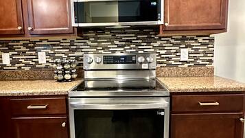 A kitchen with wooden cabinets, a stainless steel microwave, an oven, and a stovetop.