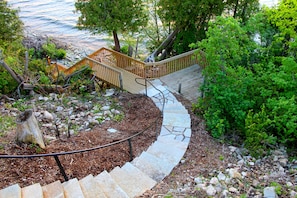 A stone staircase leading to a wooden deck with a view of the water.