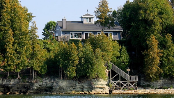 A house with a dock extending into a body of water, surrounded by trees.