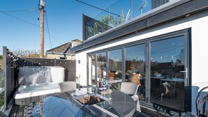 Une terrasse extérieure moderne, dotée d'une table en verre, de chaises en osier et d'un jacuzzi.